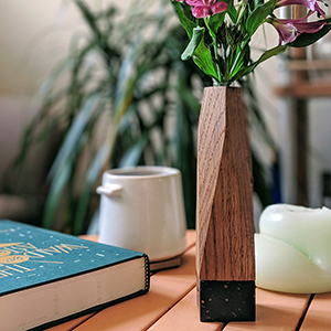 A wooden vase with a stone base on an orange table.